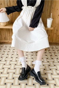 Gros plan sur des chaussettes blanches en dentelle avec des mocassins noirs à plateforme