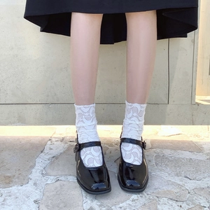 Detail of white moon pattern lace socks paired with black patent leather Mary Jane shoes