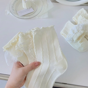 Détails de chaussettes mi-mollet en dentelle crème avec rubans élégants et texture douce