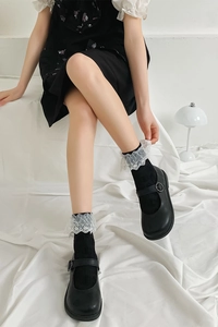Détail de chaussettes noires en coton avec dentelle blanche brodée à double épaisseur et froufrous