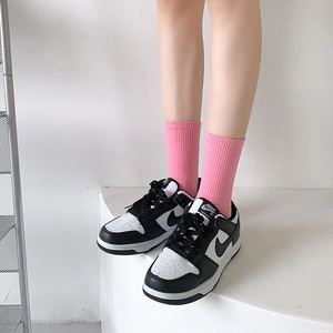 Detail of pink ribbed mid-tube five-finger socks worn with classic black and white sneakers