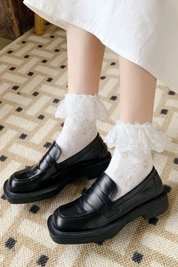 Gros plan sur les chaussettes en dentelle à volants et chaussures Lolita noires