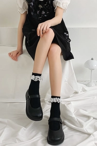 Gros plan de chaussettes noires à dentelle blanche et chaussures Mary Jane en cuir noir