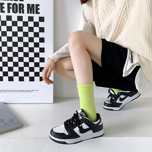Close-up of black and white leather sneakers paired with vibrant green mid-calf socks
