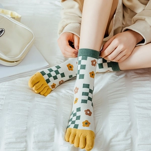 Detail von grünen Fünfzehensocken mit Schachbrettmuster und Blumen auf weichem Bettzeug