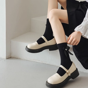 Détail de chaussures Mary Jane à plateforme avec bas à nœuds noirs sur escalier blanc