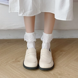 Mocassins crème en cuir avec chaussettes en dentelle blanche sur parquet bois