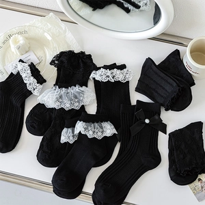 Détail de chaussettes Lolita noires avec dentelle blanche et nœuds papillon élégants