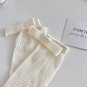 Détail de chaussettes côtelées blanc crème avec un nœud en satin et une maille douce