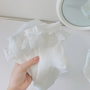 Gros plan de chaussettes blanches en tricot avec volants en dentelle et broderie florale