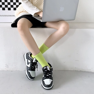 Detail of neon green cotton rib knit mid-calf socks shown in a minimalist lifestyle setting