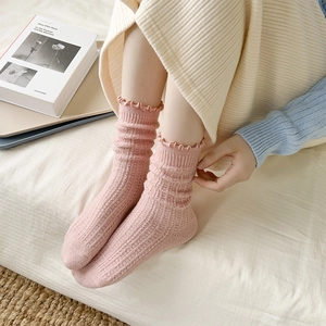 Detail of pink wool-blend socks featuring ruffled cuffs and ribbed knit texture