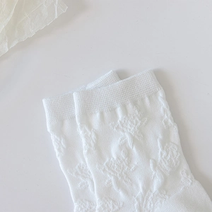 Détail de chaussettes Lolita blanches avec jacquard floral en relief et bords volantés