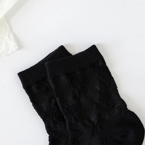 Détail de chaussettes mi-mollet noires avec motif jacquard floral et bords côtelés