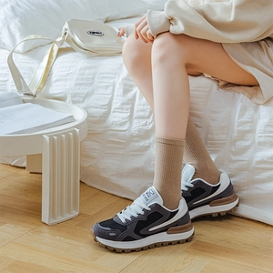 Detail of vintage patchwork sneakers styled with khaki crew socks in a cozy indoor setting