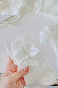 Détail de chaussettes Lolita blanches avec un nœud en satin et une perle élégante décorative