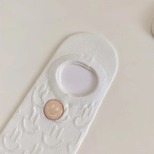 Detail of white no-show socks featuring cute yellow smiley face embroidery and mesh texture
