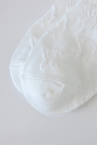 Vue macro détaillée de chaussettes Lolita blanches avec broderie florale délicate