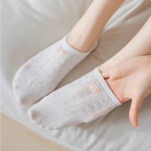 Detail of white low cut sock showing breathable mesh texture and pink bow decoration