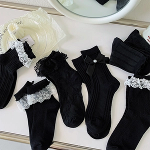 Vue détaillée de chaussettes noires avec dentelle blanche, nœuds et accents de perles