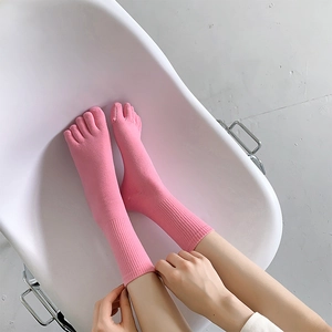 Detail of bright pink five-finger socks featuring ribbed cuffs and mid-calf length