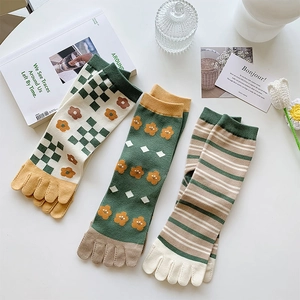 Details von drei Paar Zehensocken mit grünen Blumen- und Karomustern in Baumwolle