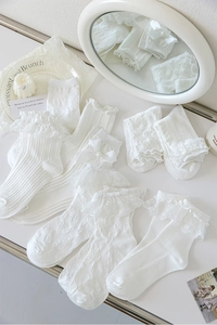Détail de chaussettes Lolita blanches avec dentelle, nœuds et accents de perles délicates