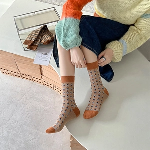 Detail of retro plaid crew socks with blue and orange geometric patterns on khaki cotton