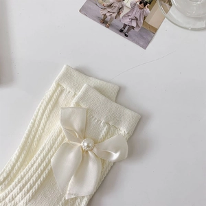Détail de chaussettes blanches en maille avec nœud en soie et ornement perle