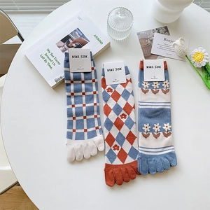 Flachbild von drei Paar Fünf-Finger-Socken mit Blumen- und Karomuster auf weißem Tisch