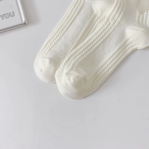 Détail de chaussettes blanches en maille avec nœud en soie et texture verticale