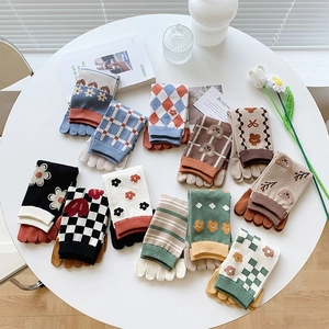 Draufsicht auf bunte Fünf-Finger-Socken aus Baumwolle mit Blumen- und Karomustern auf Tisch