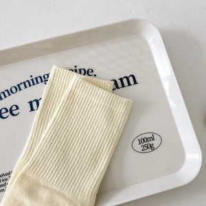 Detailed view of cream-colored mid-calf five-toe socks with ribbed cotton texture