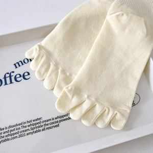 Close-up of beige knit five-finger socks showing toe separation on a white tray