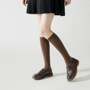 Détail de la maille des chaussettes hautes marron avec des mocassins en cuir vintage