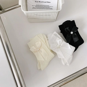 Détail de chaussettes en tricot torsadé avec nœuds en soie et perles en plusieurs tons