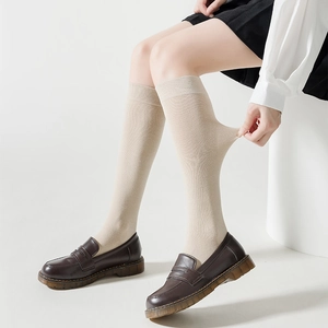 Chaussettes hautes beiges extensibles en maille montrant leur grande élasticité