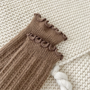 Detail of ruffled cuff and vertical ribbed knit texture on brown wool socks