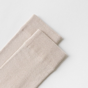 Gros plan de chaussettes en coton beige montrant les bords côtelés et la maille douce