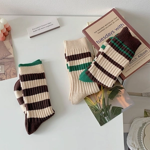 Detailed flat lay of striped knit crew socks in brown and beige on a white desk