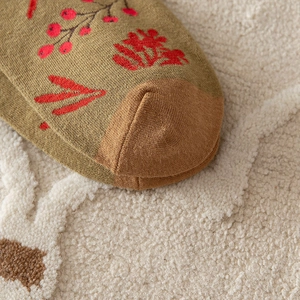 Close-up of olive green knitted sock with brown toe and red berry floral pattern detail
