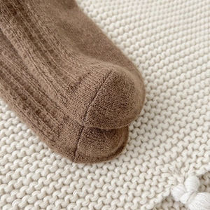 Detailed macro view of dark brown wool socks showing ribbed knit texture and flat toe seams