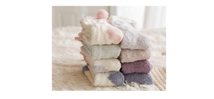Detail of soft coral fleece socks with plush pom-poms in pastel macaron colors