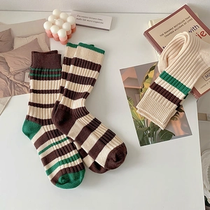 Detailed knit texture of beige and brown striped crew socks in a cozy home setting