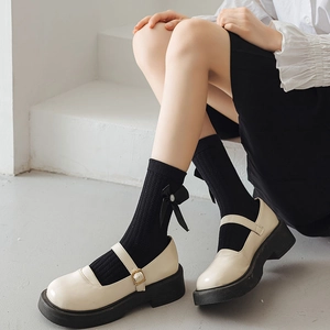Chaussures Mary Jane blanches avec chaussettes à nœuds noirs et style écolière douce