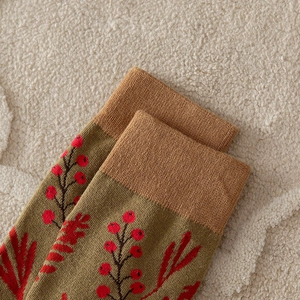 Close-up of olive green socks with red berry patterns on soft faux fur background