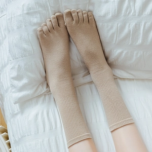 Women's minimalist khaki cotton five-finger socks with ribbed design on a white bed