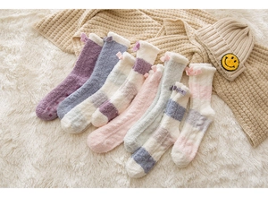 Detail of soft coral fleece thermal socks with ribbon bows on a cozy plush rug