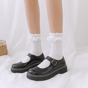 Détail de chaussettes blanches à volants avec chaussures Mary Jane noires et surpiqûres