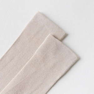 Detailed close-up of light beige over-knee socks in high-density fine knitted fabric